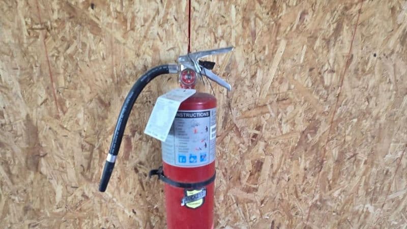 Fire extinguisher is mounted or secured — not left lying on the ground, in the back of a truck