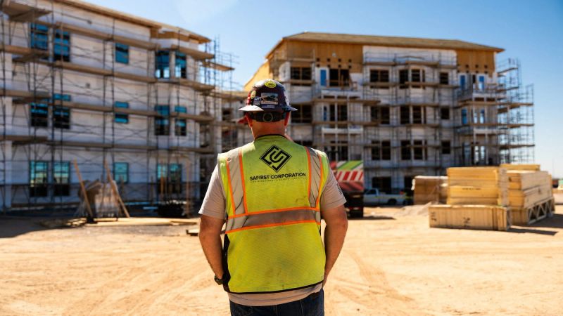 A Safirst employee from behind in vest and brim hard hat